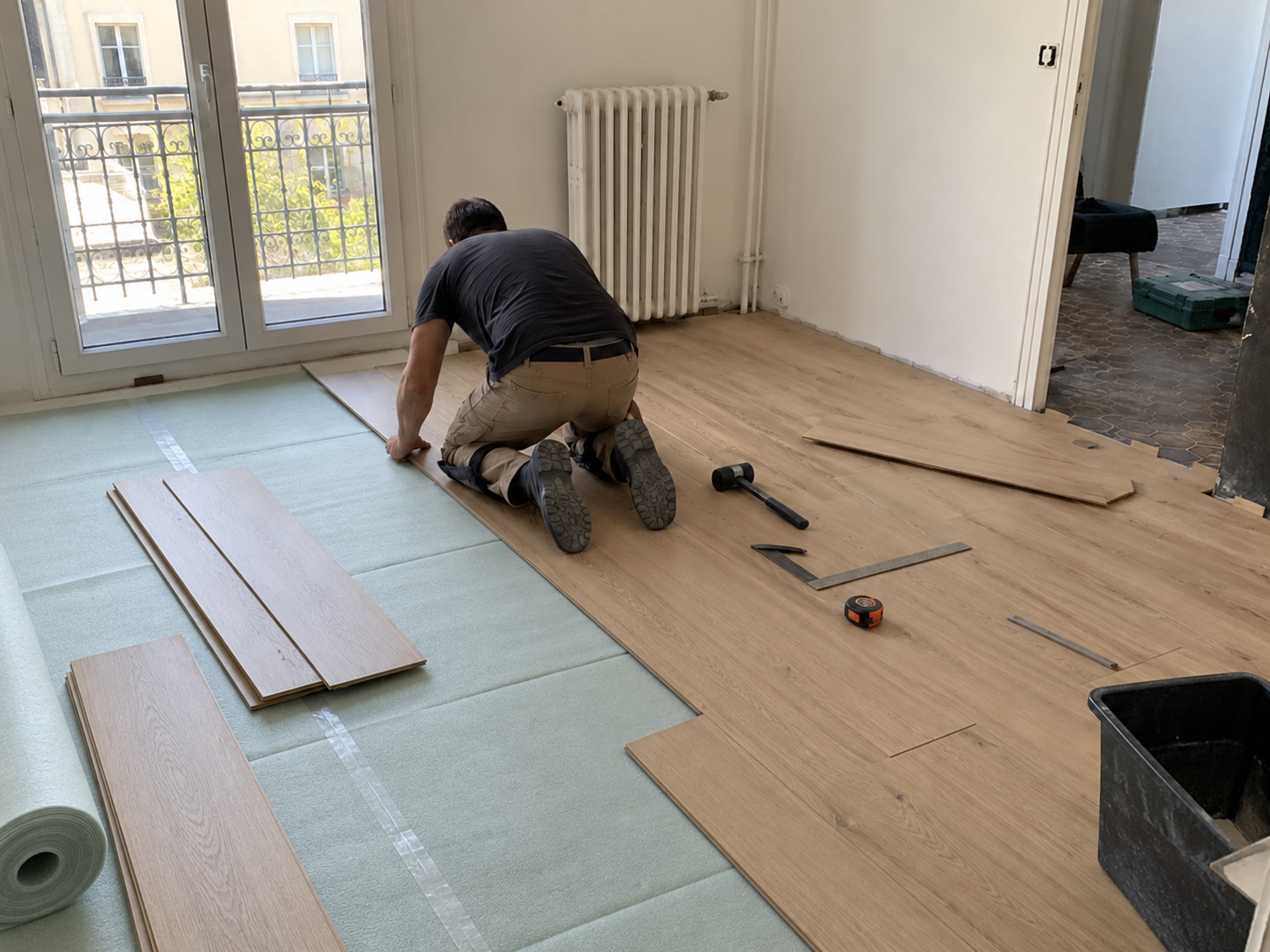 Pose de lames de parquet sur une sous-couche déroulée et assemblée dans une pièce en travaux